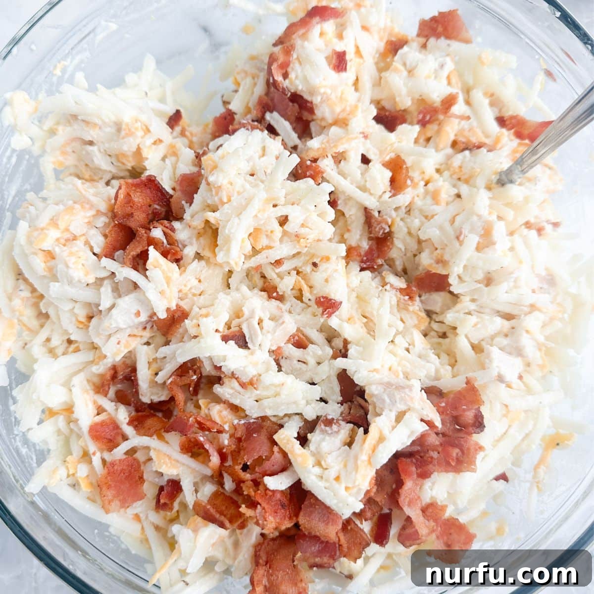 Chicken and Hash Brown Bake 4 A large bowl filled with the creamy mixture for hash brown chicken casserole, showing thawed hash browns, crumbled bacon, and shredded chicken perfectly combined.
