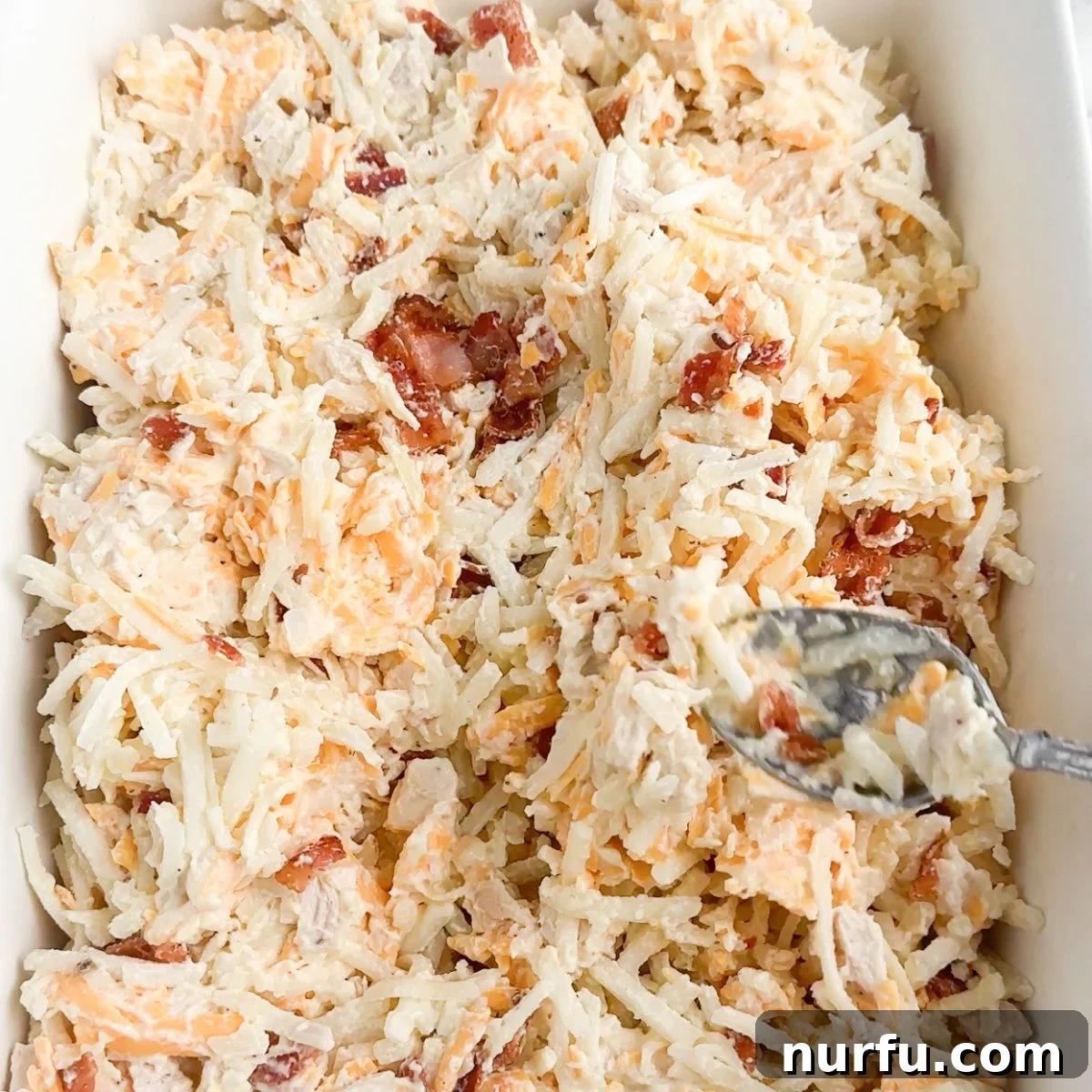 Chicken and Hash Brown Bake 5 A baking dish filled with the uncooked chicken, bacon, and hash brown casserole mixture, spread evenly and ready for the topping.