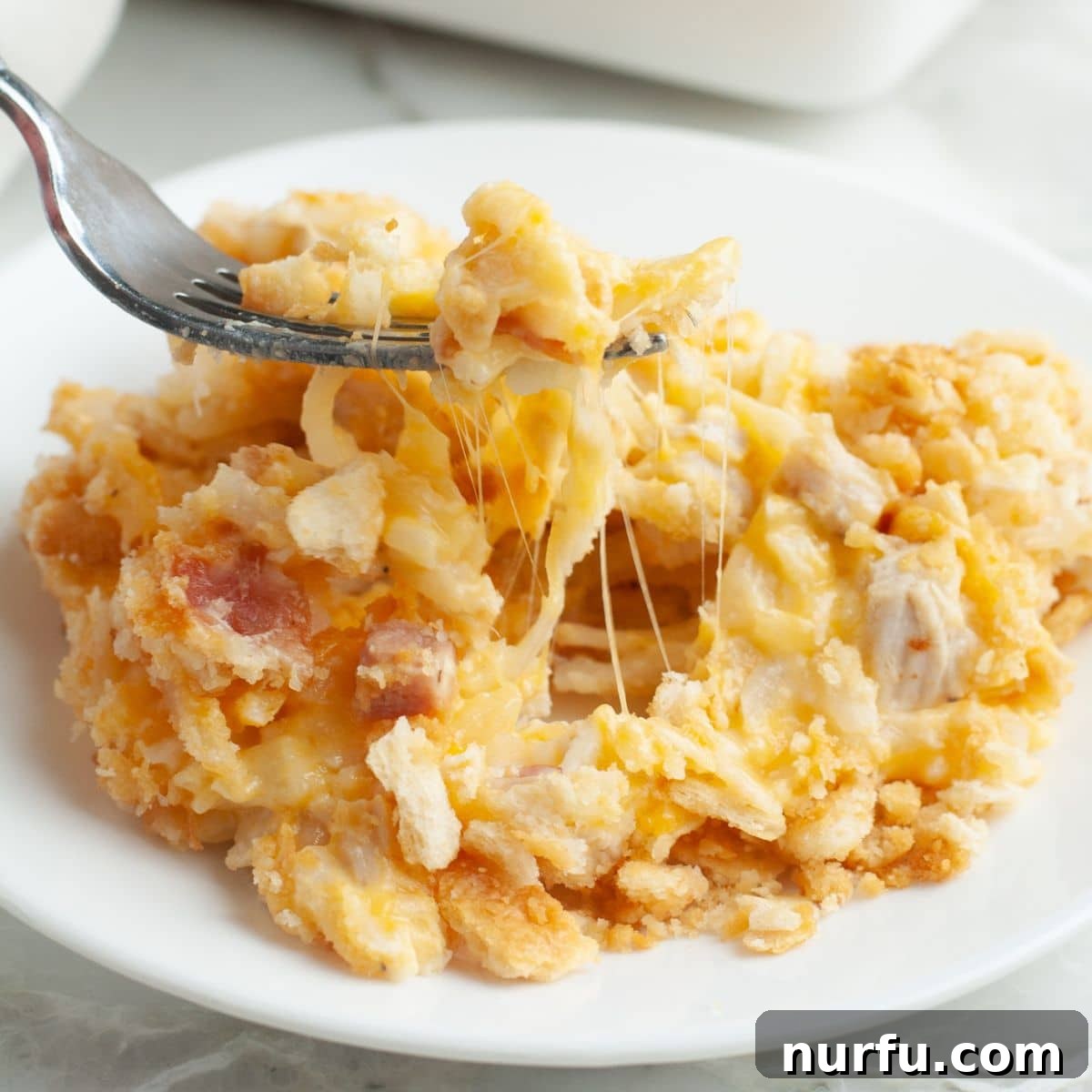 Chicken and Hash Brown Bake 7 A serving of hash brown chicken casserole on a plate with a fork, showing the delicious layers and crispy crust.