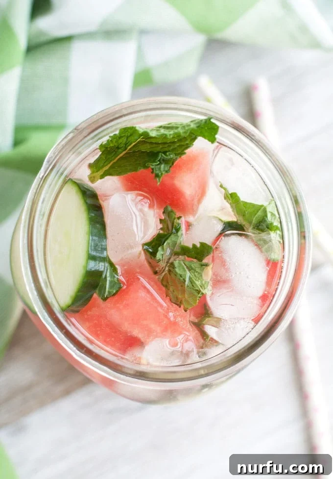 Close-up of a glass of Watermelon Detox Water with ice, watermelon, cucumber, and mint.