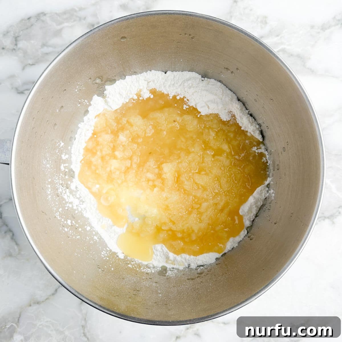 A mixing bowl shows the light, airy batter of angel food cake mix combined with crushed pineapple, ready for baking.