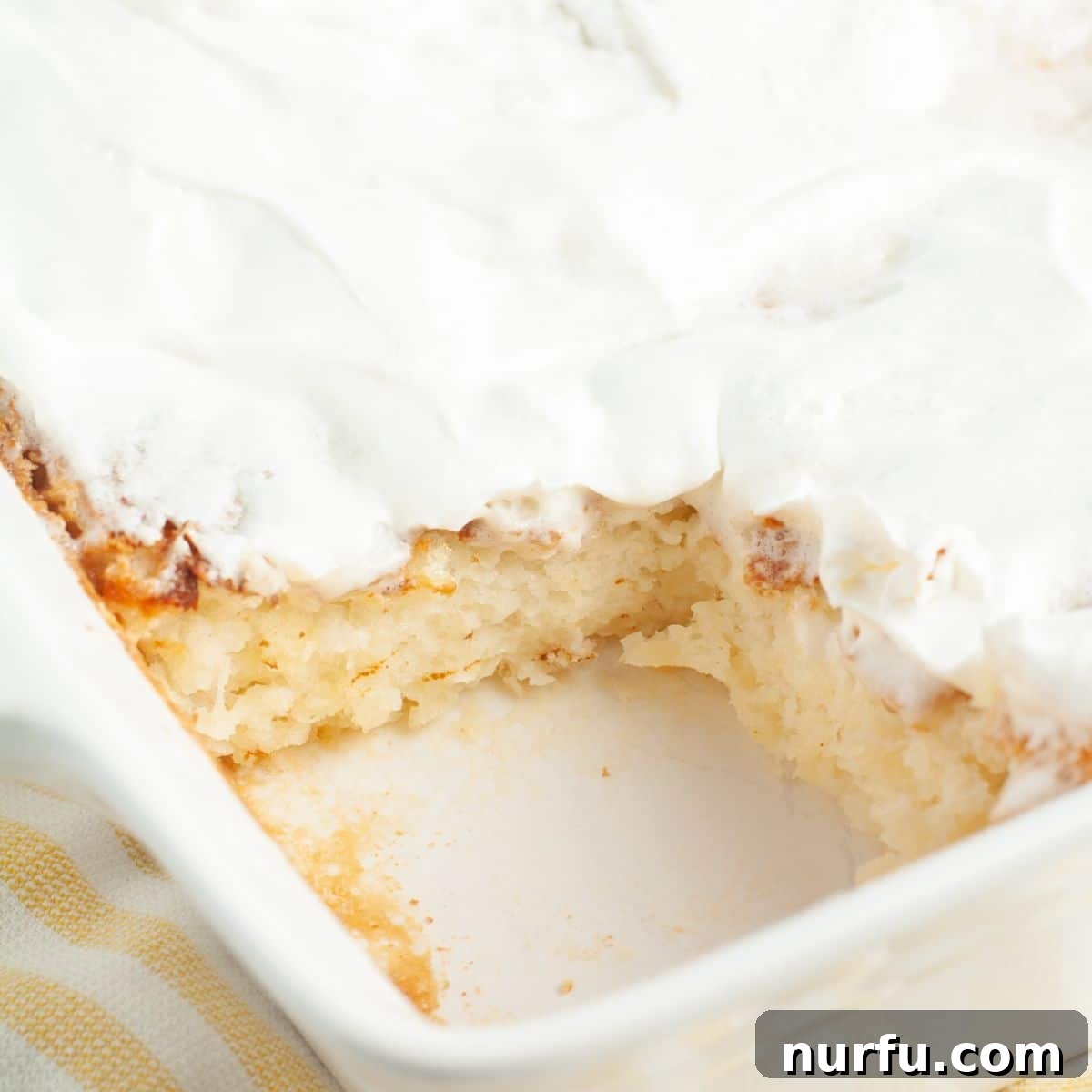 A 9x13 inch baking dish of golden-brown angel food cake is beautifully topped with creamy Cool Whip, ready to be served.