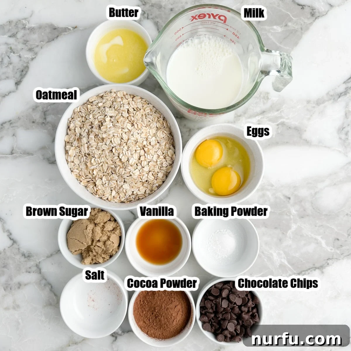 Decadent Chocolate Baked Oats 3 A selection of ingredients for chocolate baked oatmeal laid out on a table: oats, milk, brown sugar, eggs, chocolate chips, butter, cocoa powder, and baking powder.
