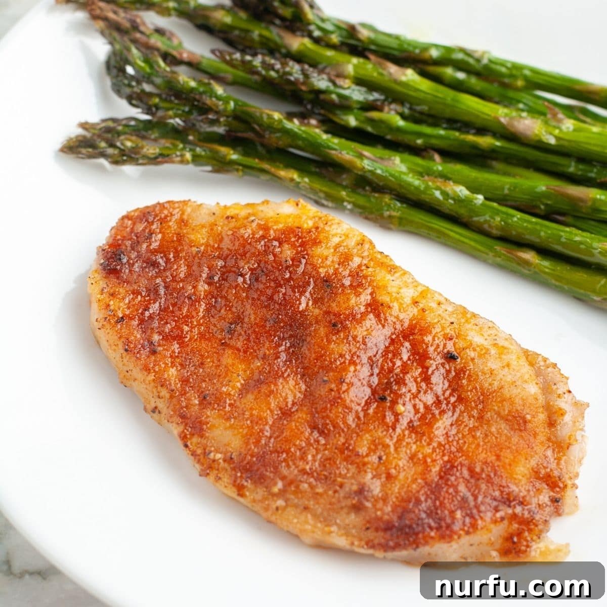 31 Effortless Friday Feasts for a Relaxing Night In 25 Pork chop on a plate with asparagus.