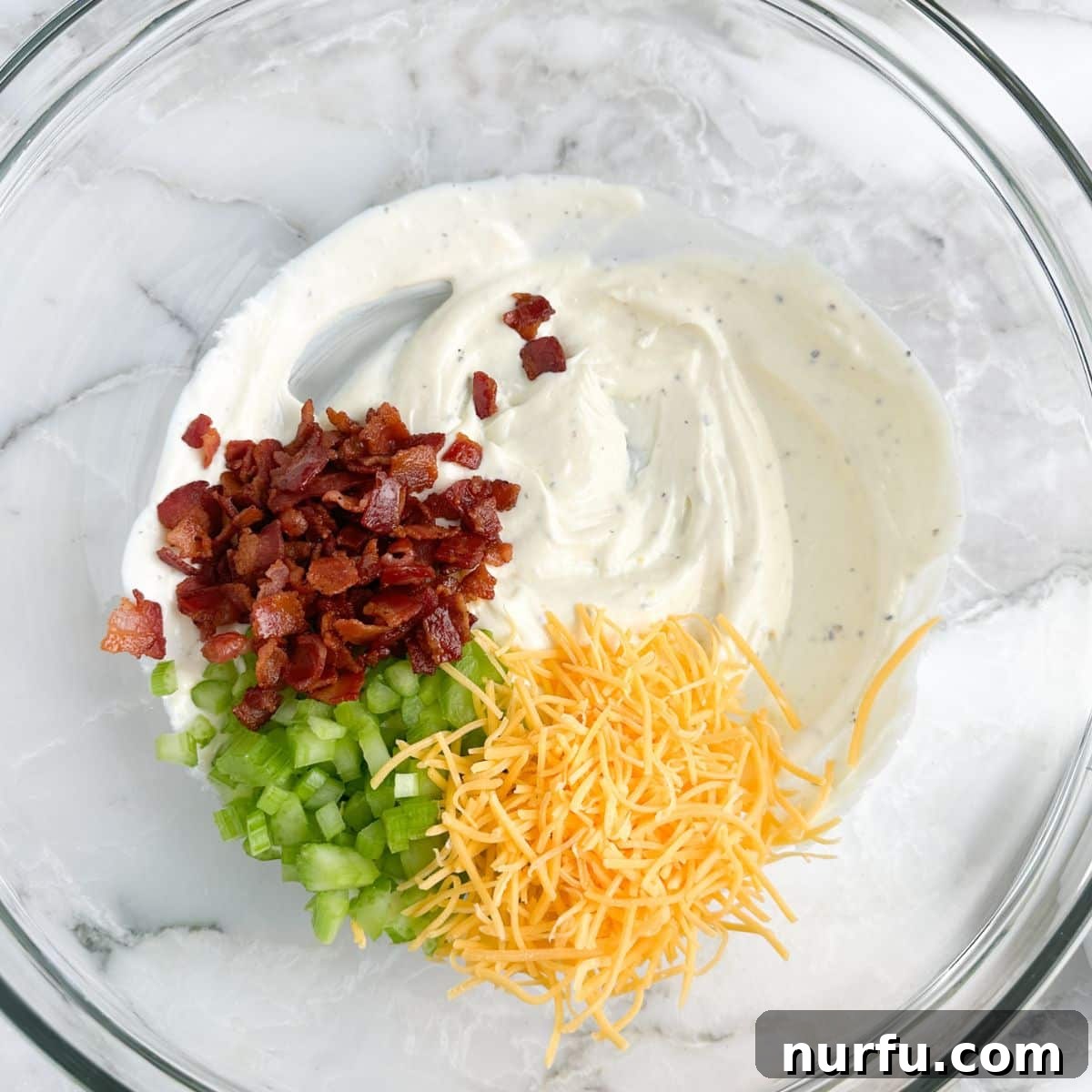 Homemade Sassy Scotty Chicken Salad 6 A mixing bowl filled with creamy mayonnaise, crunchy bacon crumbles, fresh diced celery, and rich shredded cheese, forming the vibrant components of the Sassy Scotty chicken salad before the chicken is added.