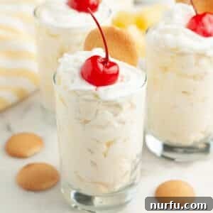 Small glasses with pineapple pudding topped with whipped cream and cherry.