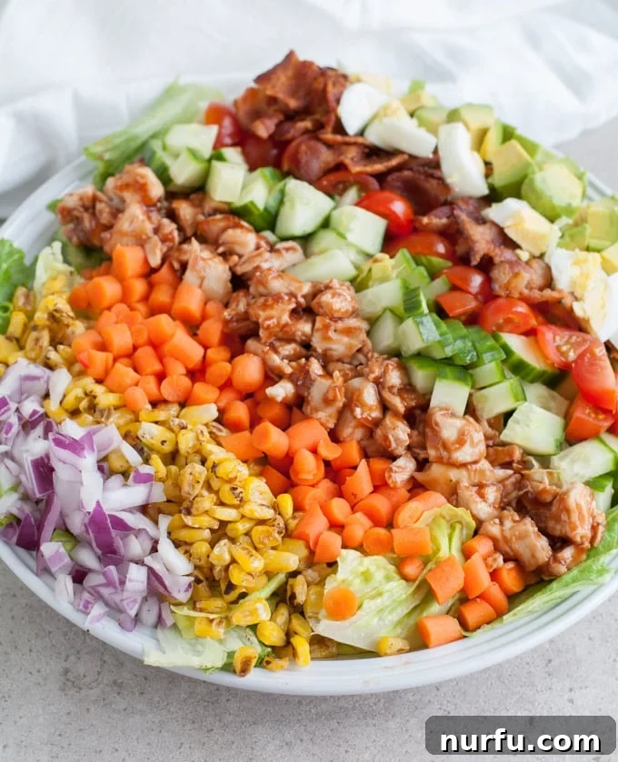 Smoky BBQ Chicken Cobb Salad 3 Overhead shot of a delicious BBQ chicken cobb salad, showcasing its layered ingredients including succulent chicken, crispy bacon bits, sliced hard-boiled eggs, fresh vegetables, and a creamy dressing.
