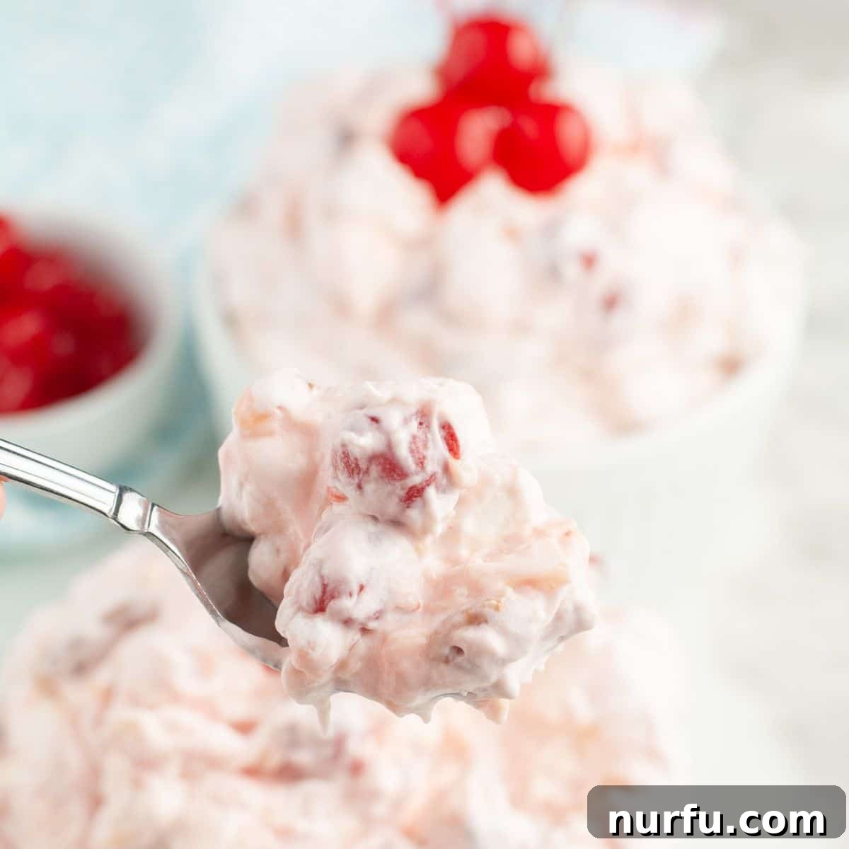 A spoon scooping a portion of creamy cherry fluff, highlighting its delicious texture.