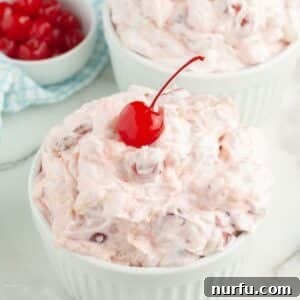 Bowl of cherry fluff topped with a cherry.