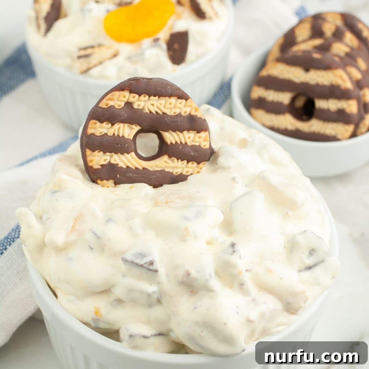 The Ultimate Cookie Salad 7 Bowl with creamy dessert salad, topped with a whole fudge stripe cookie as garnish.
