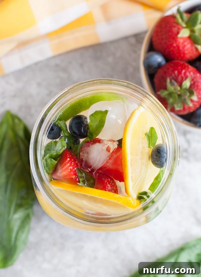 Glass filled with various fresh fruits and mint leaves for infused water