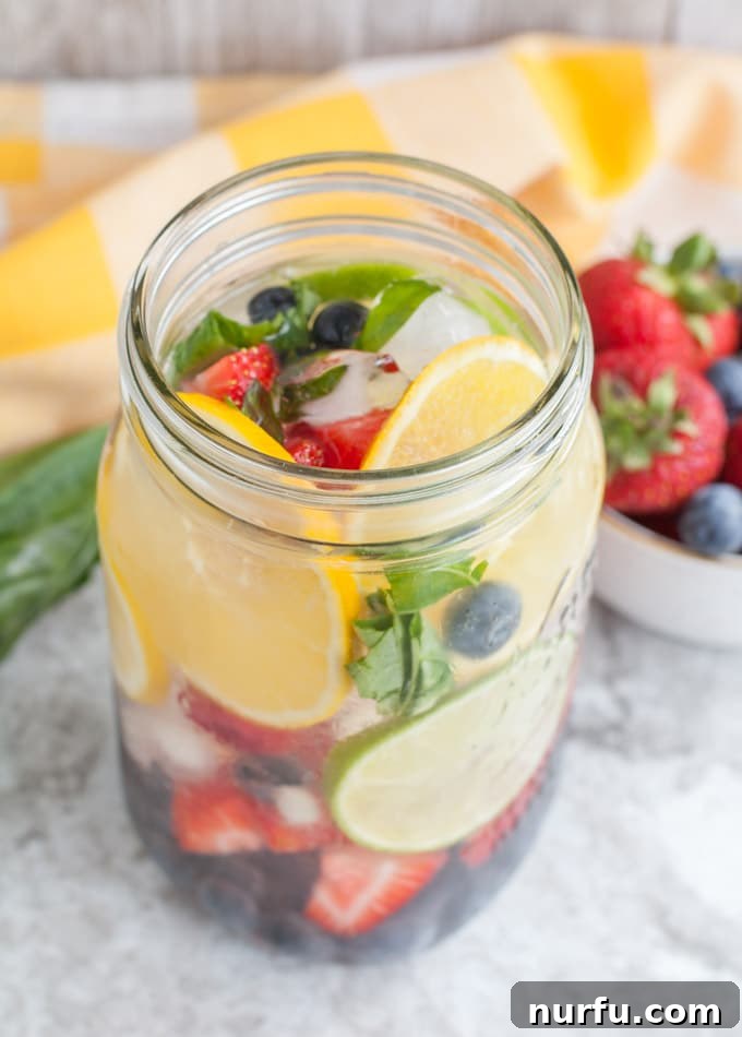 Rainbow Detox Water full of fruit and fresh basil in a clear pitcher