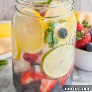 Jar of water with lemon, lime, blueberries and strawberries for Rainbow Infused Water