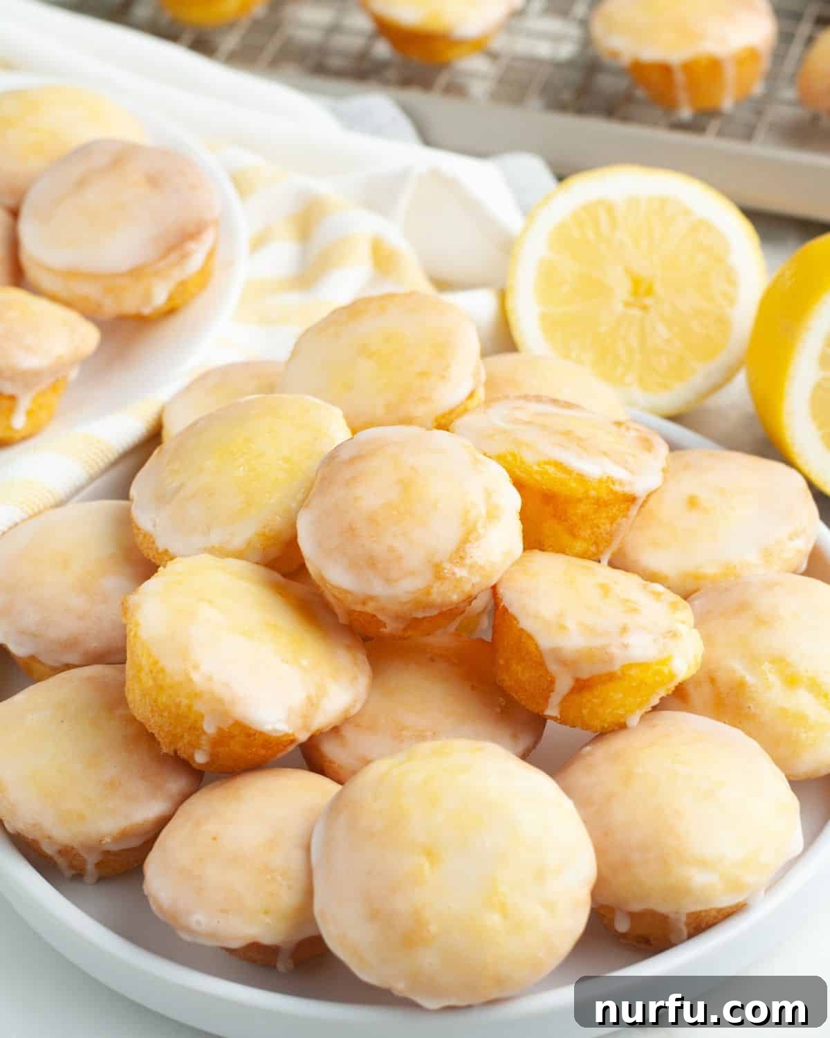 A plate piled high with golden-yellow lemon blossoms, each glistening with a fresh lemon glaze.
