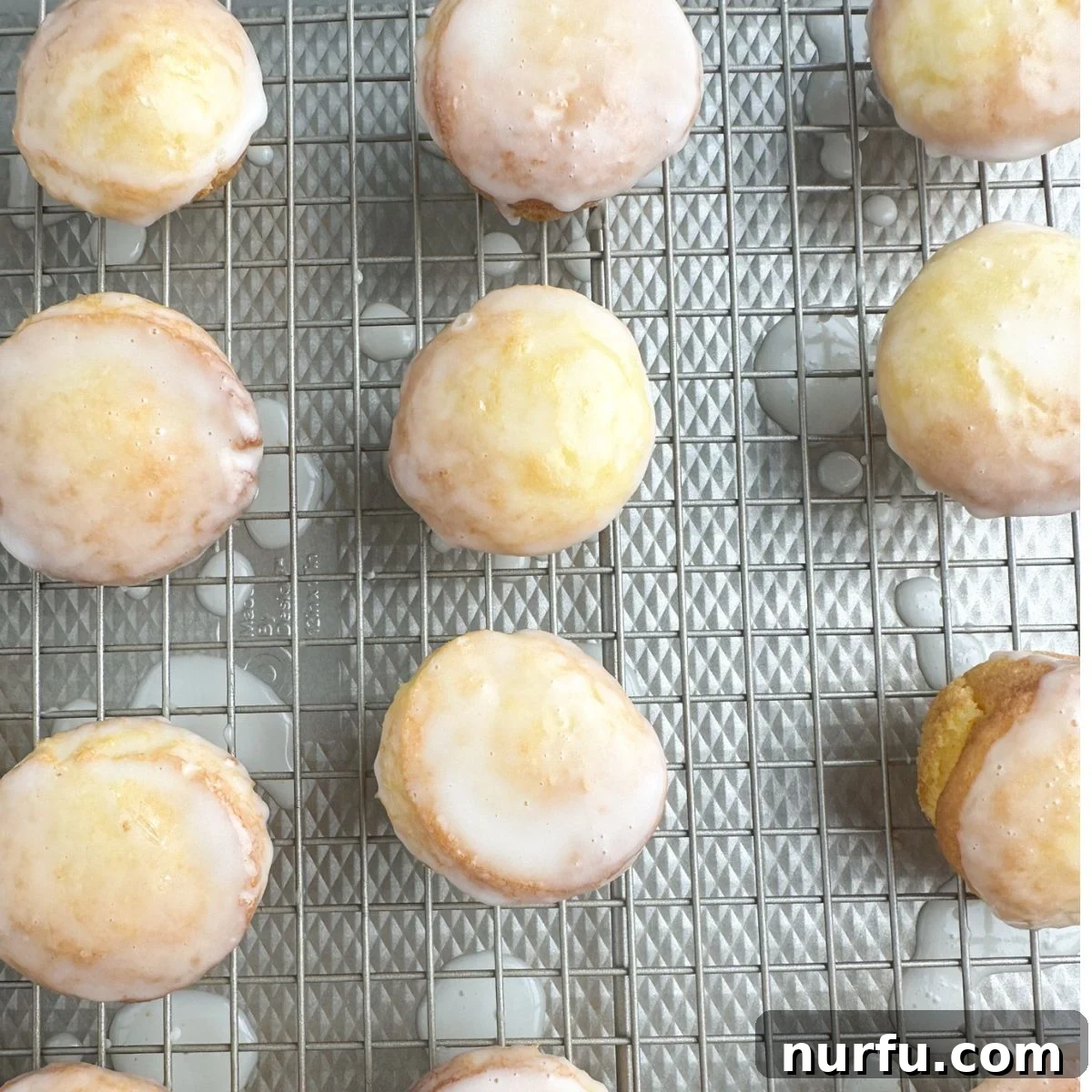 A cooling rack laden with freshly baked, glazed mini lemon cakes, showcasing their delicate texture and vibrant color.