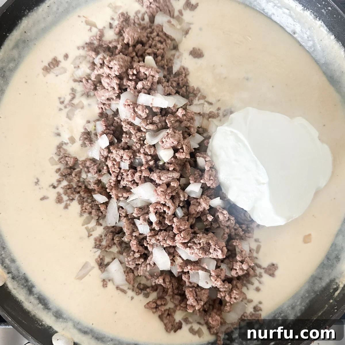 Creamy Stroganoff Potato Casserole 4 Skillet filled with creamy ground beef and sour cream sauce, ready for layering.