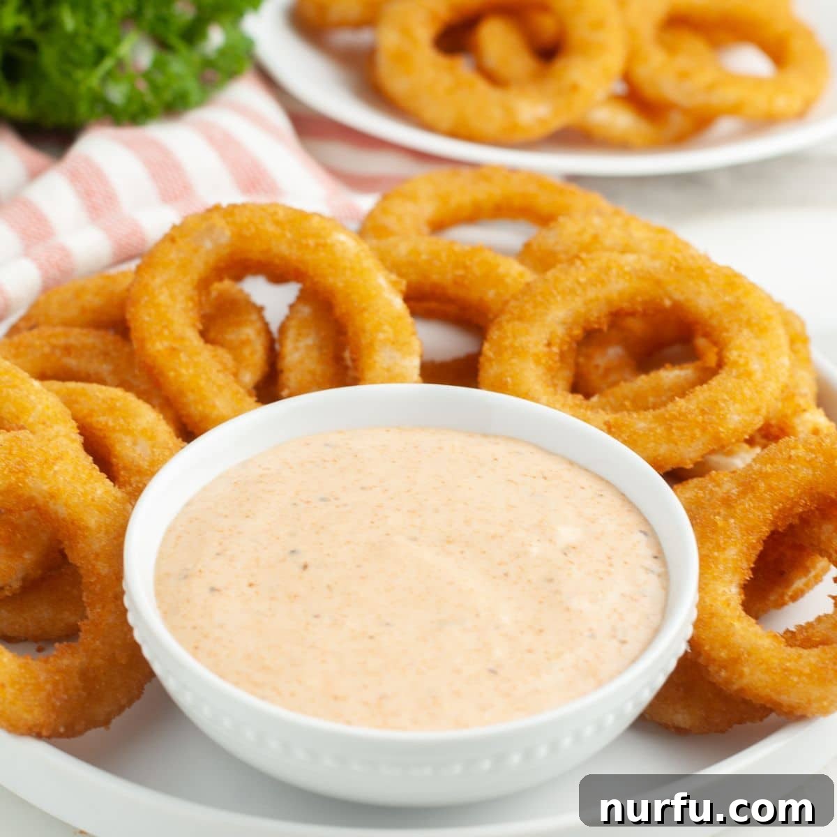 Signature Bloomin' Onion Sauce 5 A tantalizing spread featuring a bowl of the vibrant Bloomin' Onion Sauce surrounded by perfectly golden, crispy onion rings, inviting you to dip.
