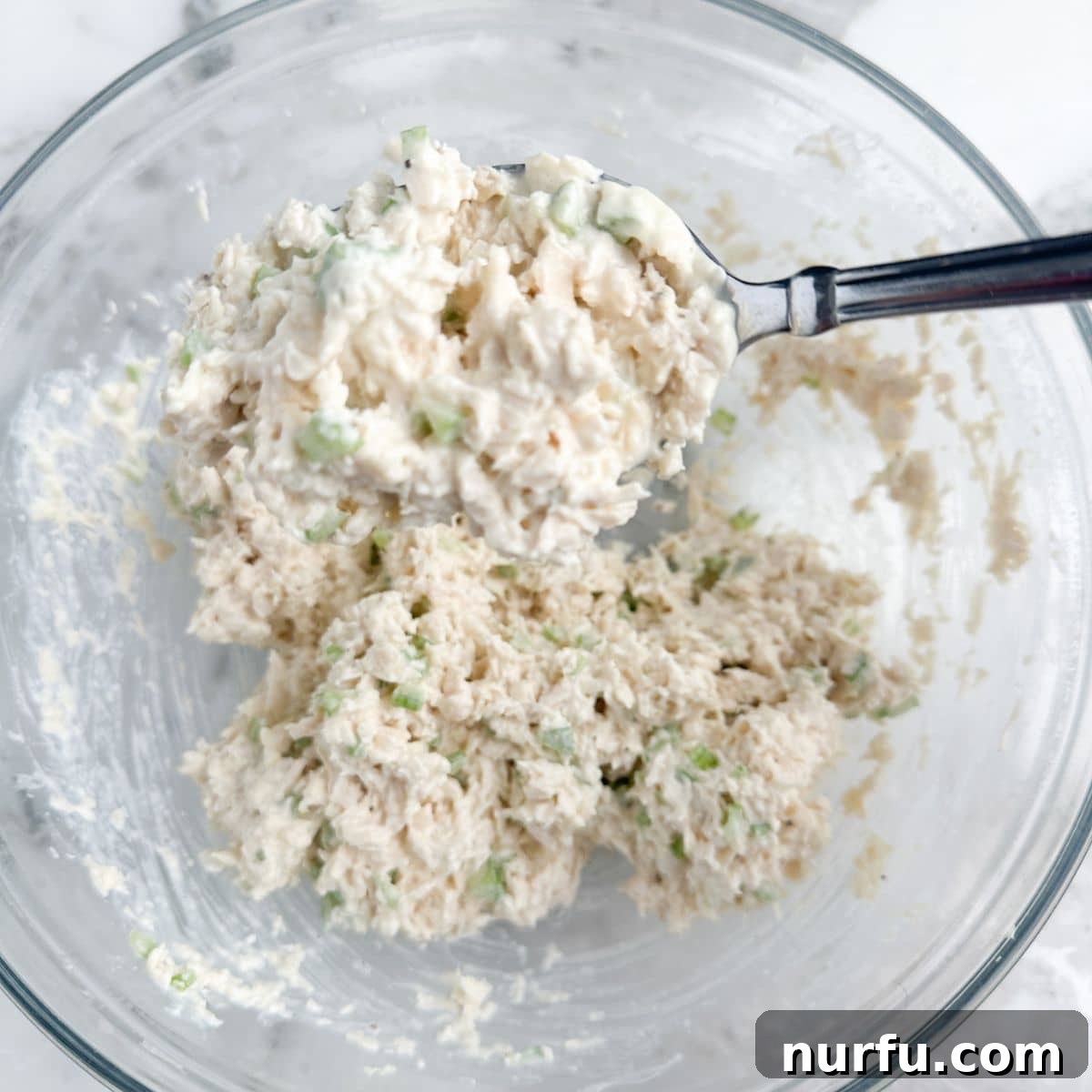 Homemade Classic Carol Chicken Salad Chick 5 A bowl of freshly made Classic Carol chicken salad with a spoon, ready to be enjoyed.