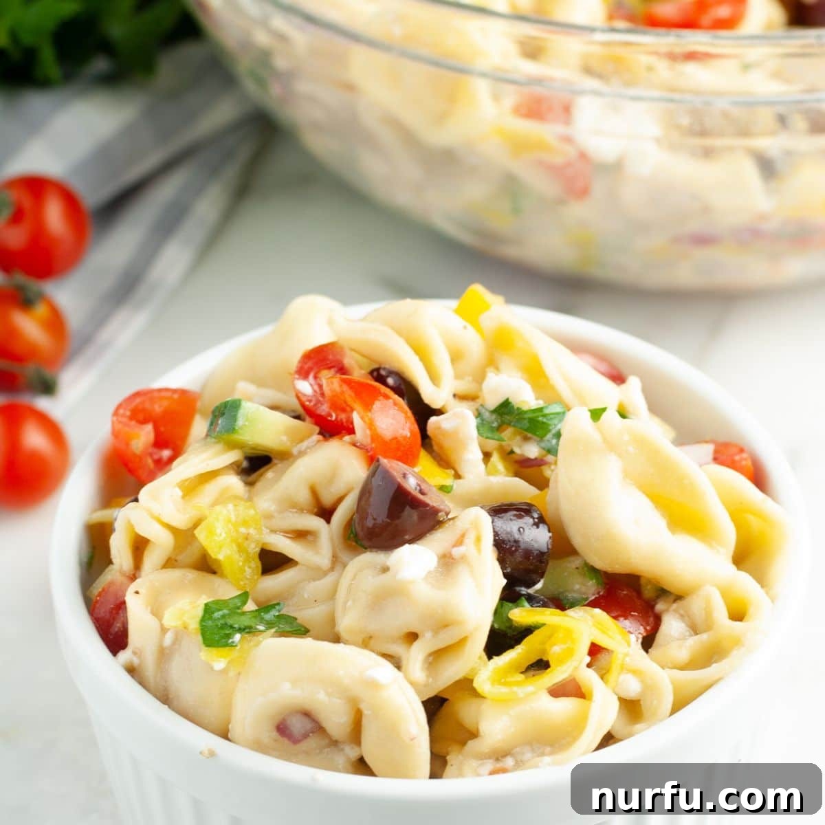 Vibrant Greek Tortellini Pasta Salad 5 A large serving bowl filled with the completed Greek tortellini pasta salad, garnished with fresh parsley.