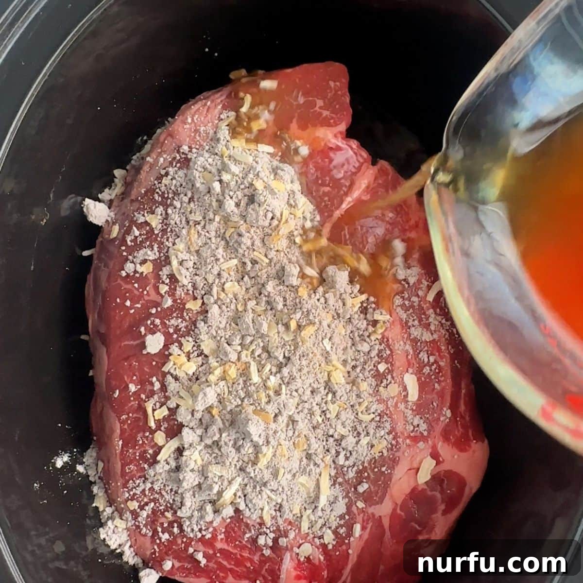 Fall Apart Slow Cooker BBQ Beef 5 A raw chuck roast in a slow cooker, covered with onion soup mix, as beef broth is poured into the pot around the meat, initiating the slow cooking process.