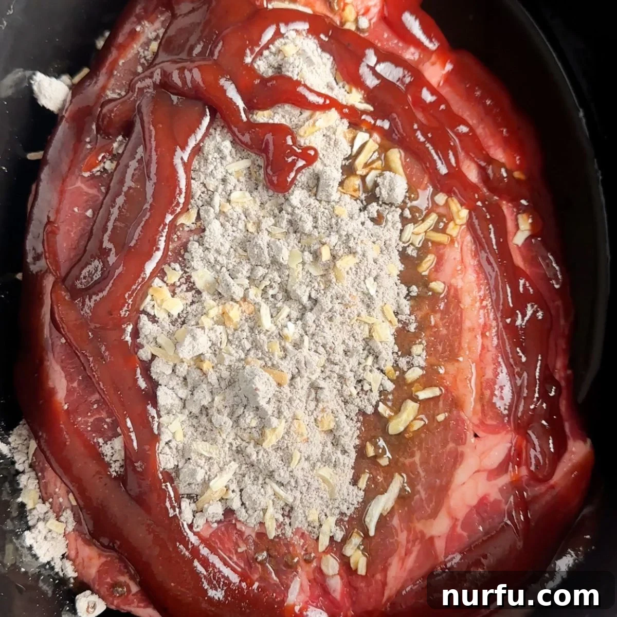 Fall Apart Slow Cooker BBQ Beef 6 A raw chuck roast in a slow cooker, seasoned with onion soup mix and beef broth, now topped with a generous pour of barbecue sauce, ready for cooking.