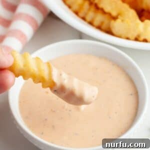 A bowl of fry sauce with a crinkle fry.