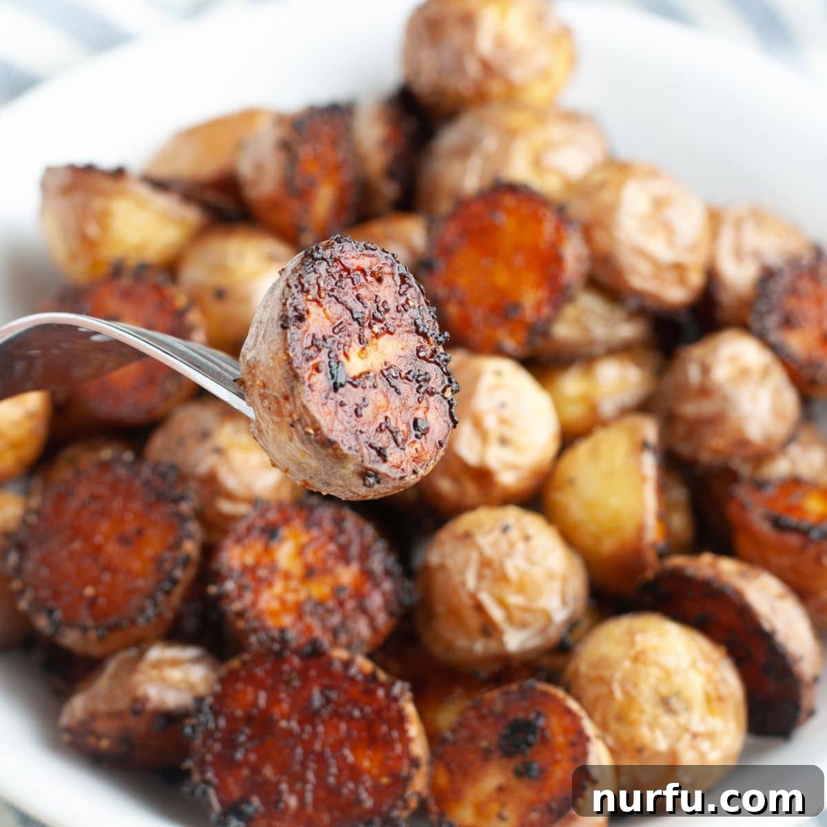 A fork holding a single perfectly roasted potato, highlighting its golden crispness.