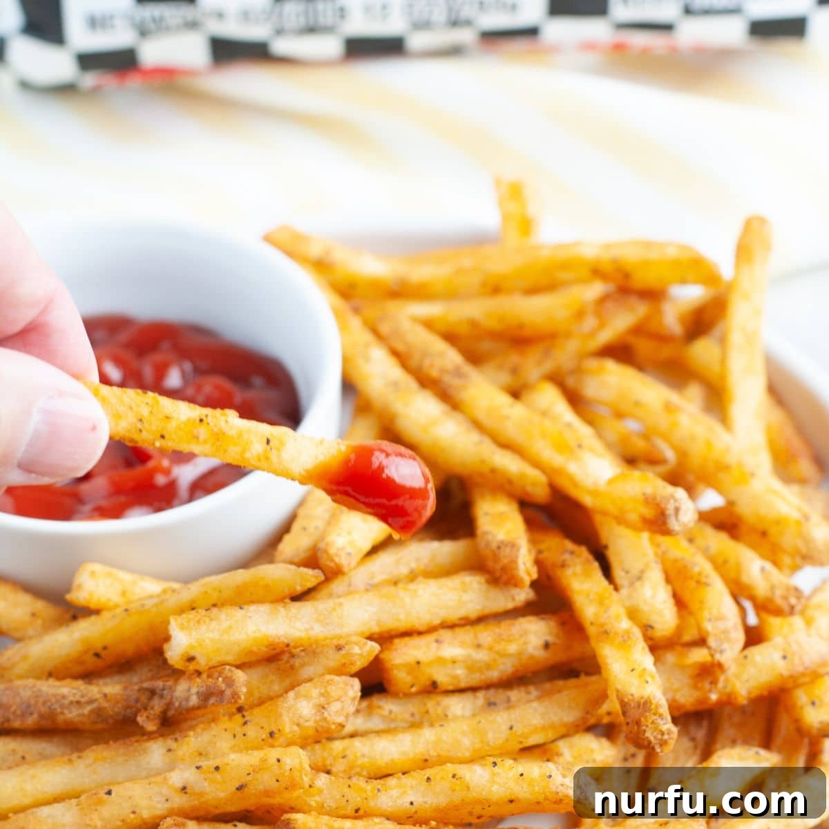 Crispy Checkers Fries in the Air Fryer 6 French fries dipped in ketchup.