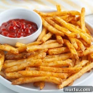 French fries on a plate with bowl of ketchup.