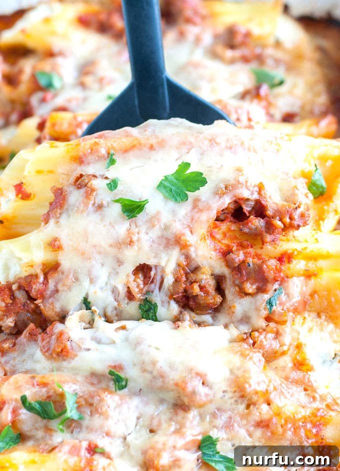Best Sausage Manicotti Recipe Close-up of baked manicotti with sausage sauce and melted cheese, ready to be served.