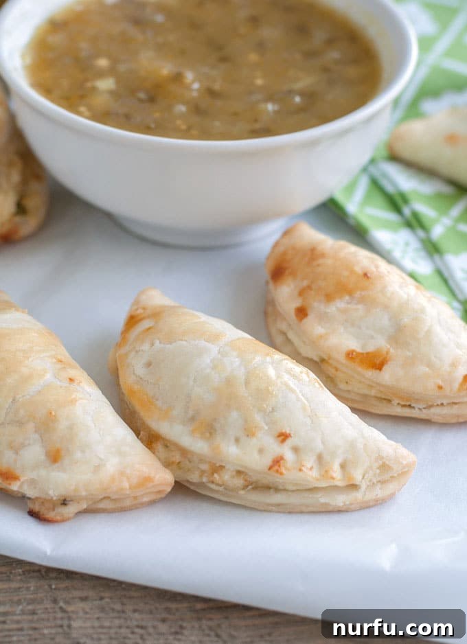 Salsa Verde Empanadas ready to serve Freshly baked Salsa Verde Empanadas on parchment paper with a bowl of Pace Salsa Verde.