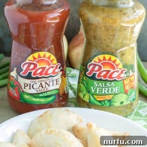 Bottles of salsa on table with bowl of empanadas.