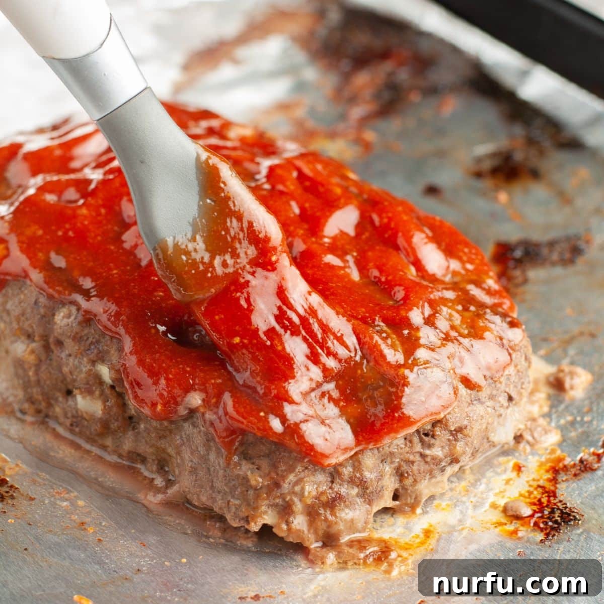 Ultimate Meatloaf Sauce 6 Brushing meatloaf glaze on a meatloaf, showing the glossy, caramelized finish.