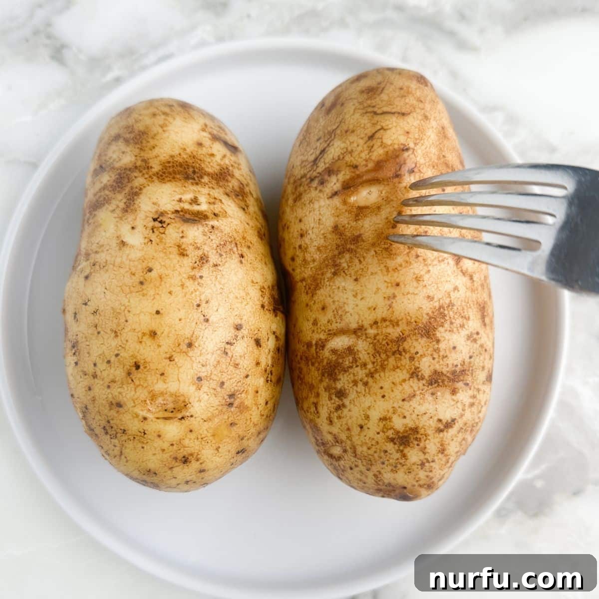 A fork piercing a baked potato, checking for tenderness, a crucial step for microwave baked potatoes.