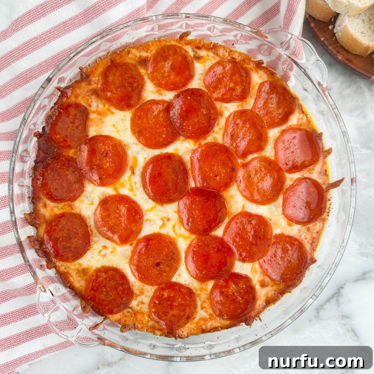 Ultimate Party Pizza Dip 8 A perfectly cooked pepperoni pizza dip in a pie plate, bubbling and golden, ready for eager guests to enjoy.