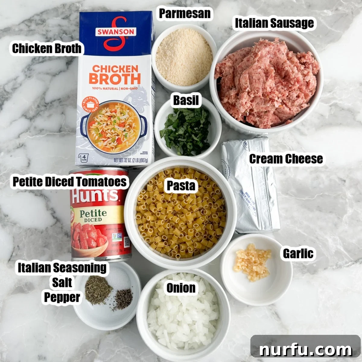 Velvety Italian Sausage and Parmesan Soup 3 A collection of key ingredients for Creamy Parmesan Italian Sausage Soup: chicken broth, uncooked Italian sausage, ditalini pasta, petite diced tomatoes, diced onion, cream cheese block, and garlic cloves.