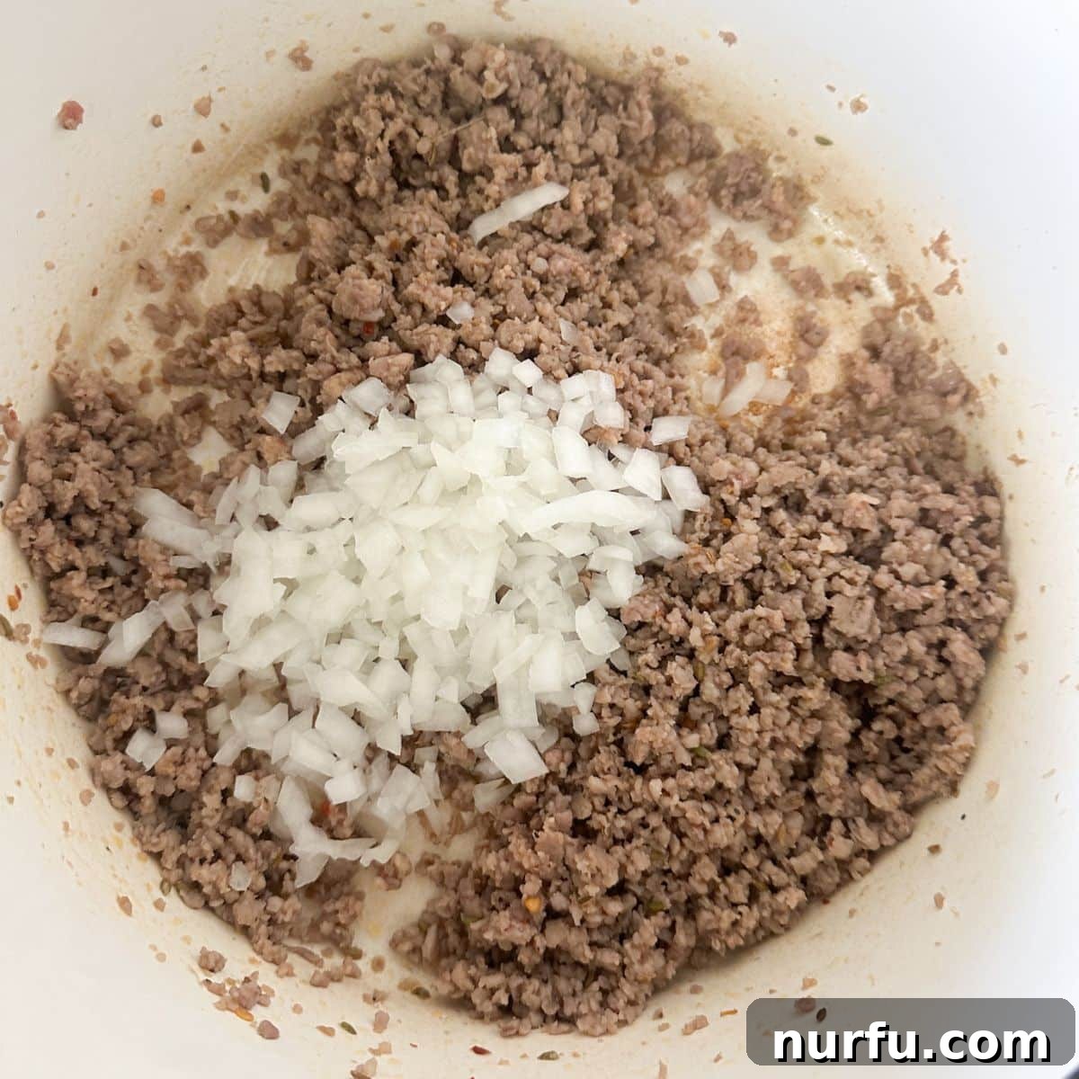Velvety Italian Sausage and Parmesan Soup 4 A pot on the stove with browned, crumbled Italian sausage and sautéed diced onions.