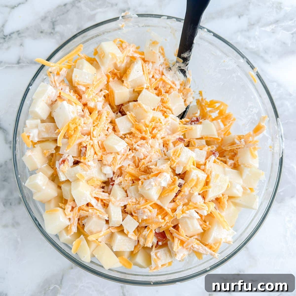 Deep South Mud Pie Potatoes 6 A bowl filled with diced potatoes generously coated in the rich, cheesy, and bacon-infused mixture.