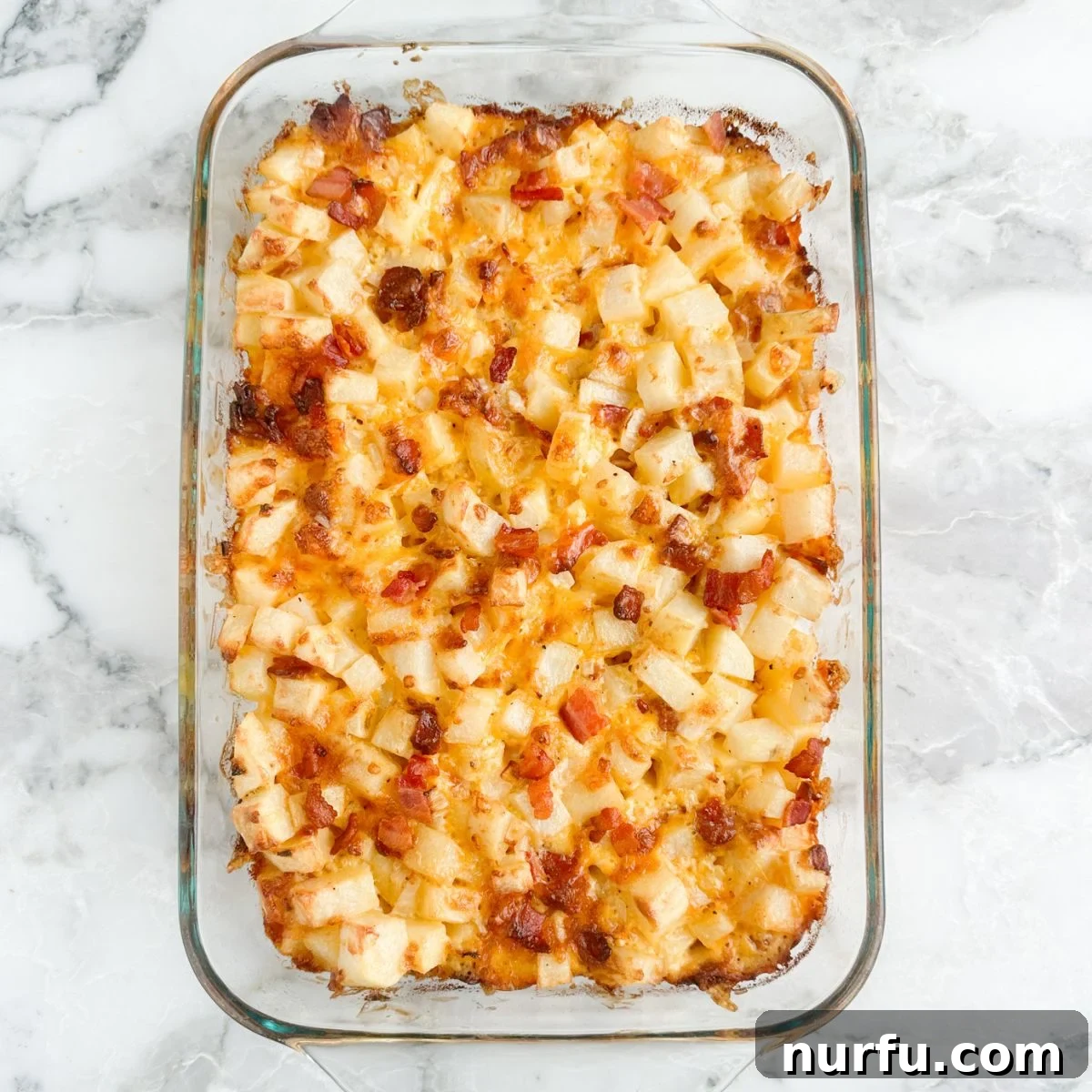 Deep South Mud Pie Potatoes 7 A baking dish showcasing golden, baked diced potatoes with crispy bacon and melted cheese.