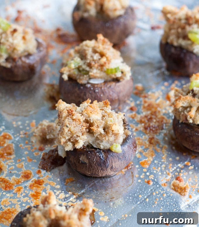 Stuffing stuffed mushrooms baking on a parchment-lined sheet, showcasing their golden-brown tops and rich filling.