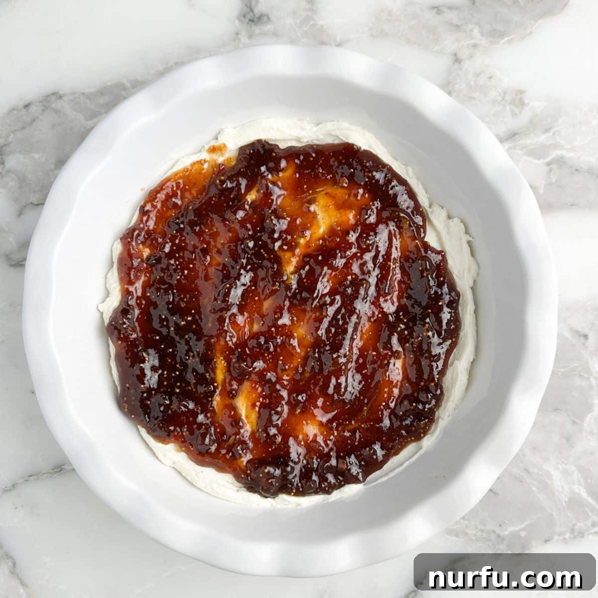 Fig & Bacon Boursin Bliss 7 A pie dish featuring the smooth cream cheese layer topped with a generous, even layer of sweet fig jam, creating a beautiful contrast.