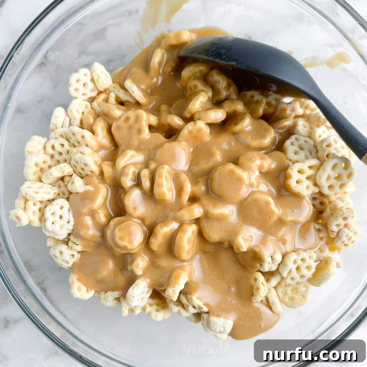 Churro Fiesta Mix 5 A large mixing bowl containing Honeycomb cereal thoroughly coated with warm, glossy caramel sauce, ready for baking.