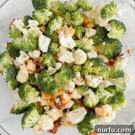 A vibrant bowl of fresh broccoli cauliflower salad, complete with crunchy additions.