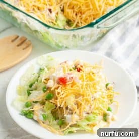 A beautiful plate of seven-layer salad, showcasing distinct layers of fresh ingredients, cheese, and tomatoes.