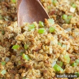 A wooden spoon delicately scooping fluffy, oven-baked stuffing from a dish.