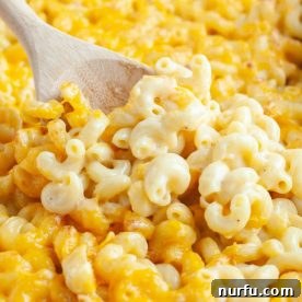 Creamy baked macaroni and cheese in a dish with a wooden spoon, ready to serve.