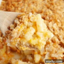 A wooden spoon serving a portion of savory-sweet pineapple casserole.