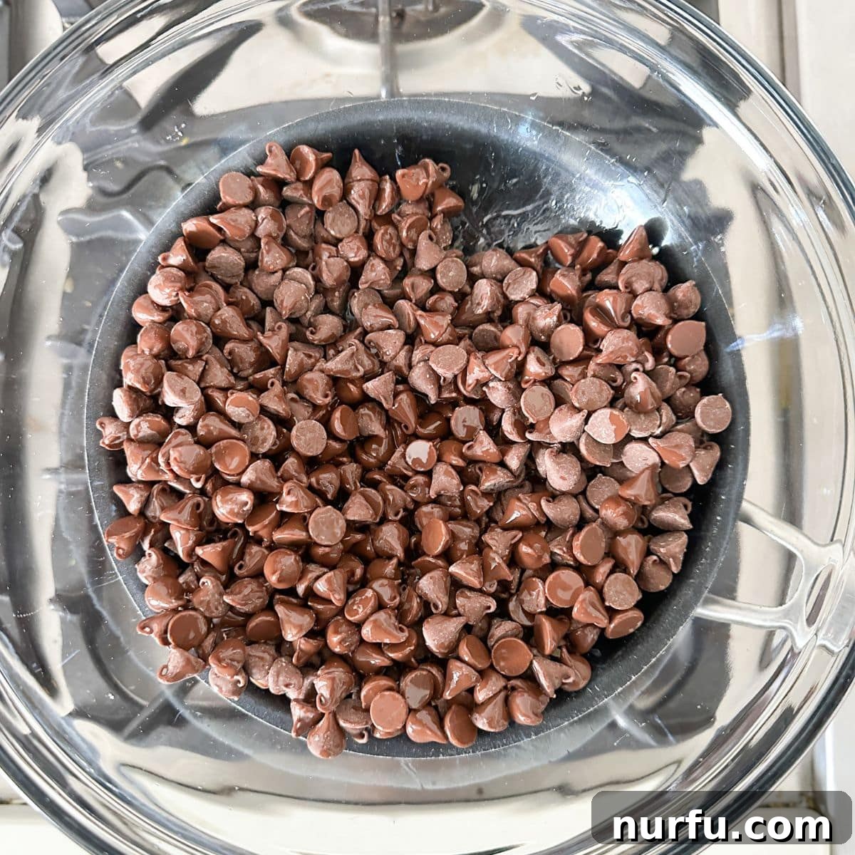 Andes Mint Chocolate Pretzel Crunch 4 A glass bowl filled with melting milk chocolate chips, heated gently over a double boiler, showing the smooth, glossy transformation of the chocolate as it liquefies.