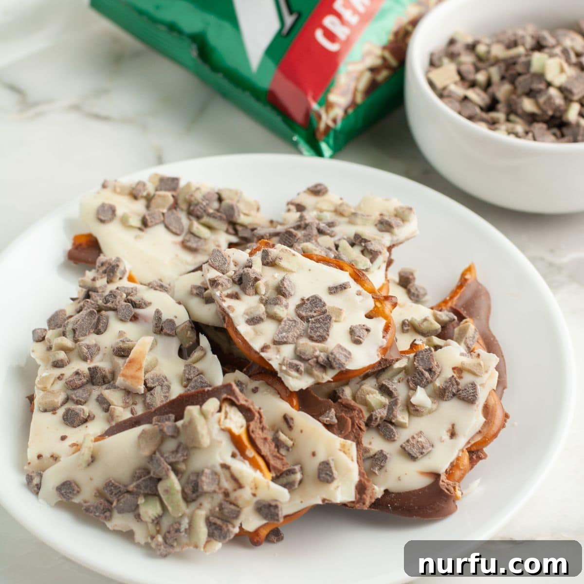Andes Mint Chocolate Pretzel Crunch 9 A beautifully arranged plate of irregularly broken Andes Mint pretzel bark pieces, ready to be served, highlighting its distinct layers and appealing mint-chocolate topping, perfect for sharing.