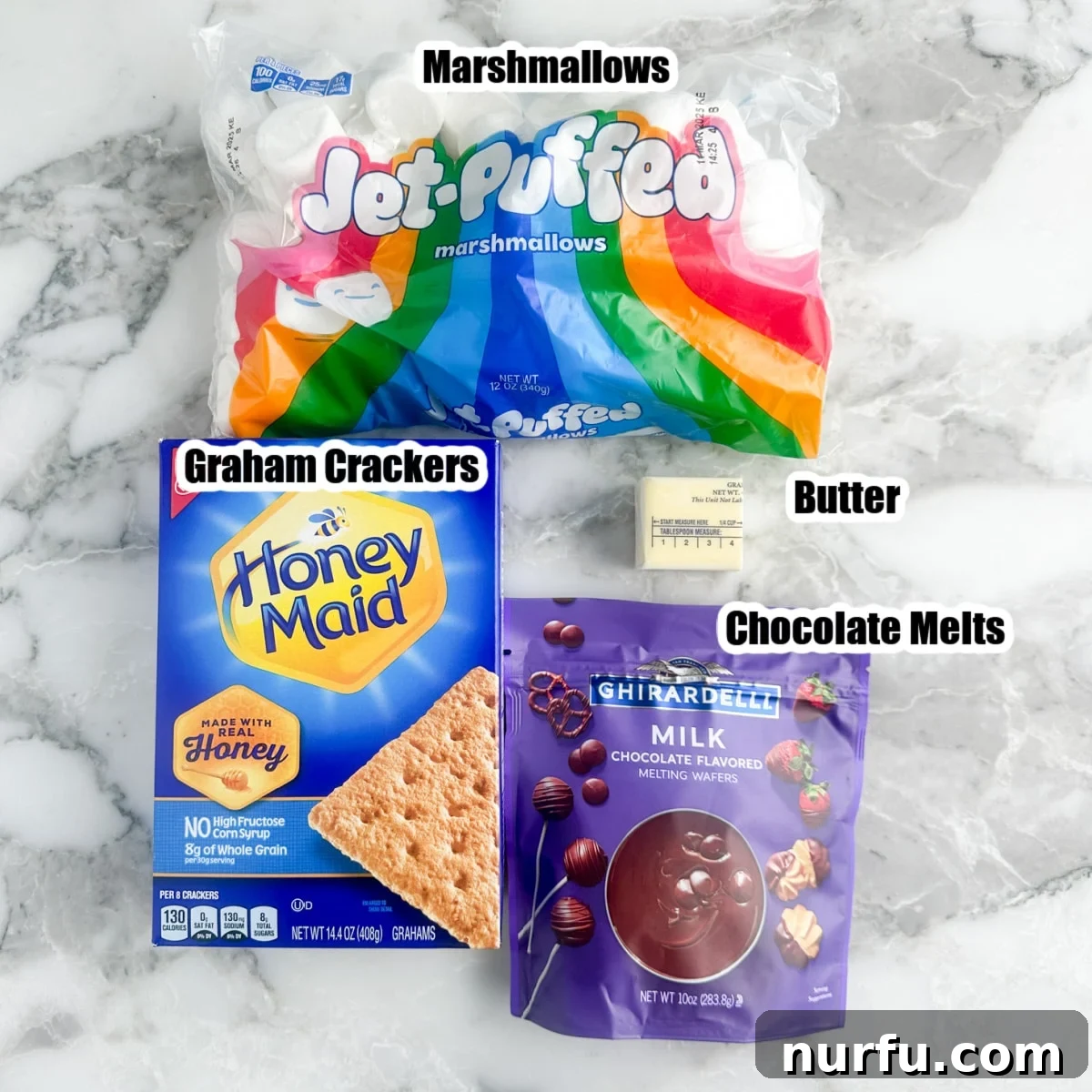 Irresistible S'mores Bark 3 A selection of S'mores bark ingredients: a box of graham crackers, a bag of marshmallows, a stick of butter, and a bag of chocolate melts.